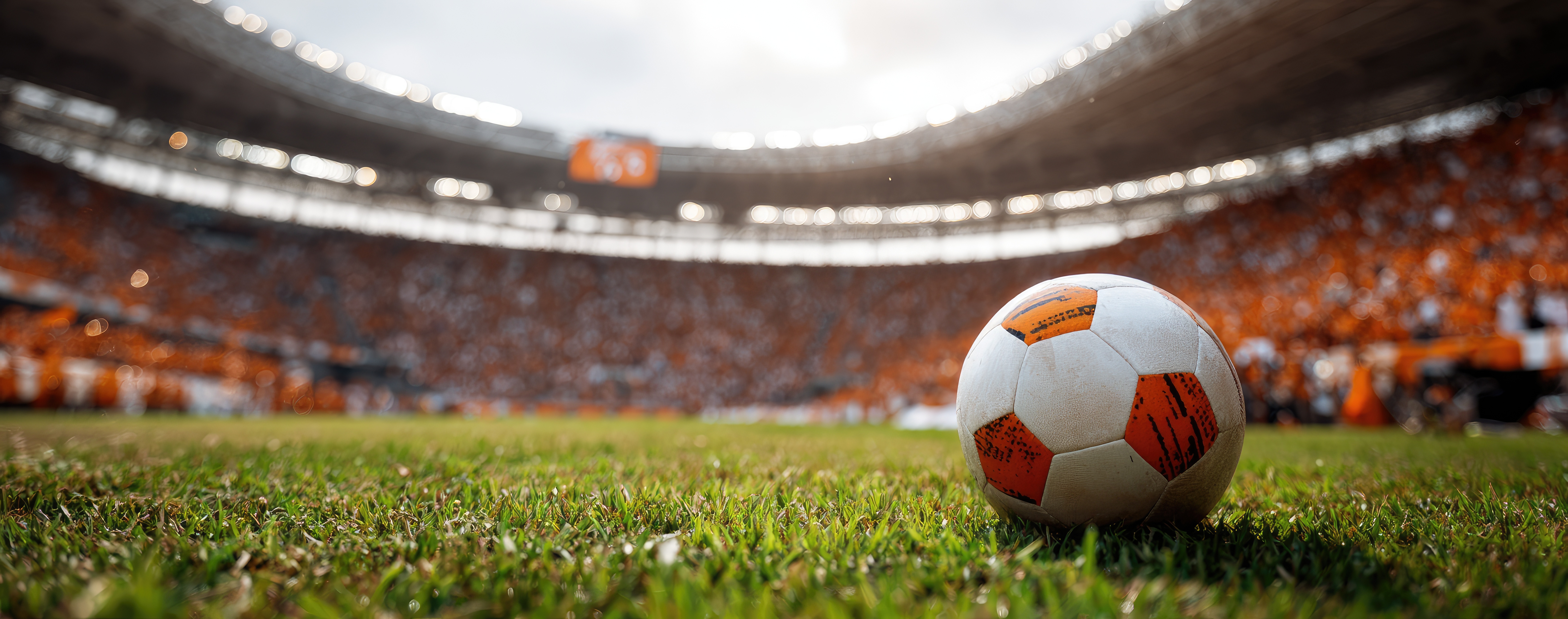 Soccer ball on grassy field, stadium in the background